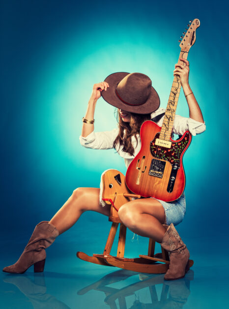 Female model wearing a hat with an electric guitar for Improve your lighting a photography workshop by Frank Doorhof